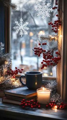 a window sill decorated with christmas decorations and candles next to a book, coffee cup, and snowflakes