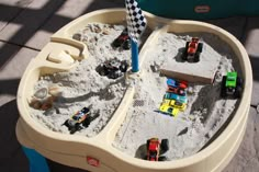 toy cars are parked in the sand on top of a play table with a checkered flag