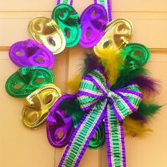 a mardi gras wreath with masks and feathers hanging on the front door,