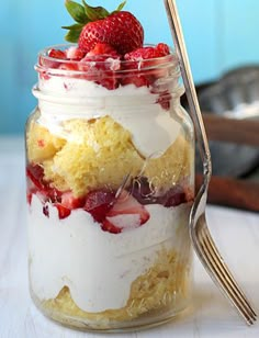 a strawberry shortcake in a jar with whipped cream and strawberries