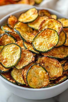 a white bowl filled with cooked zucchini on top of a marble countertop