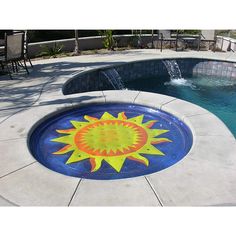 a swimming pool with a sun design painted on the side and water fountain in the middle