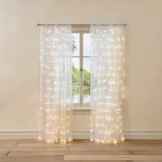 a white curtain with lights hanging from it's side in front of a window