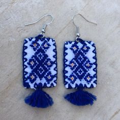 two pairs of blue and white knitted earrings with tassels hanging from hooks