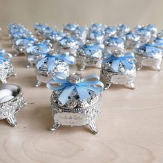 a table topped with lots of silver containers filled with blue bows