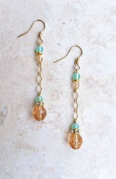 "Translucent peach and milk sea green Czech glass beaded satin gold chain drop earrings with crystal rhinestone gold spacers A little bit peachy and a little bit beachy, these simple and versatile drop earrings are the perfect summer accessory! Whether you're going to a movie in the park or a wedding on the beach, their classic minimalist design make these earrings both versatile and elegant. From a gold plated earwire hangs 4mm milky sea green and faceted pink Czech glass beads separated by a bright golden brass spacer bead.  From these beads dangle an 8mm faceted translucent peach and a 4mm faceted seafoam green Czech glass bead on a satin gold diamond link chain. A 5mm gold plated crystal rhinestone spacer separates the two focal beads and adds just enough sparkle to make these simple b Trendy 14k Gold Filled Dangle Jewelry, 14k Gold-filled Beaded Drop Earrings, Gold Dangle Earrings With Beaded Chain, Trendy 14k Gold-filled Dangle Jewelry, Wire Wrapped Czech Glass Drop Earrings, Beaded 14k Gold Filled Dangle Earrings, 14k Gold Filled Beaded Dangle Earrings, Adjustable Gold Earrings With Beaded Chain, Trendy Gold Jewelry With Dangling Beads