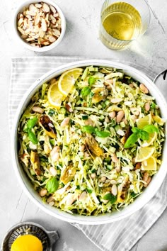 a white bowl filled with salad next to lemons and nuts