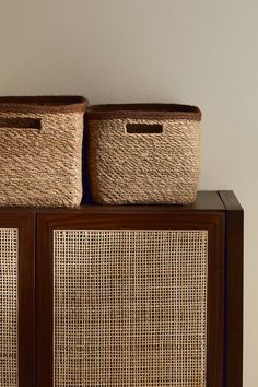 two wicker baskets sit on top of a cabinet