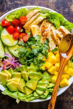 a salad with chicken, avocado, tomatoes and cucumber in it