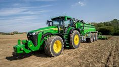 a large green tractor driving down a dirt road