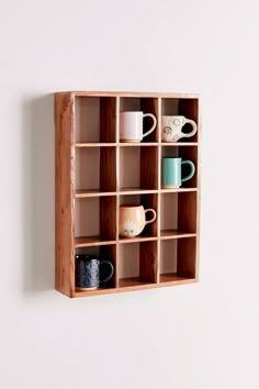 a wooden shelf filled with cups and mugs on top of white wall mounted shelves