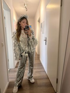 a woman taking a selfie in the mirror wearing silver sequins and holding a cell phone