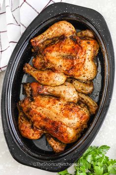 cooked chicken in a pan with parsley on the side