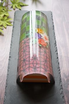 a glass vase sitting on top of a wooden table next to a potted plant