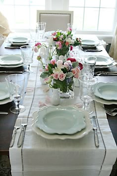 the table is set with plates, silverware and flowers