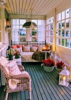 the porch is decorated with wicker furniture and flowers on it's side table