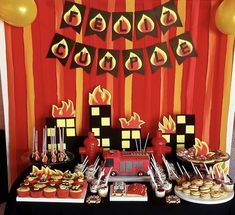 a table topped with lots of desserts next to a red and yellow striped wall