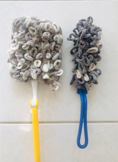 two mop heads are sitting on the wall next to each other, one has a yellow handle