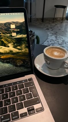 an open laptop computer sitting on top of a table next to a cup of coffee