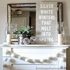 a fireplace mantel with a silver winter sign on it and candles in vases