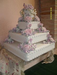 a three tiered white wedding cake with pink flowers on the top and bottom layer