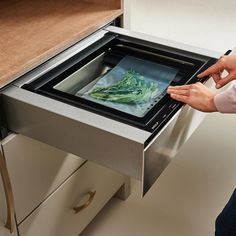 a woman is opening the drawer of an appliance that has been placed on it