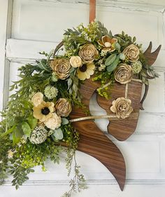 a wooden horse head with flowers and greenery hanging on the side of a building