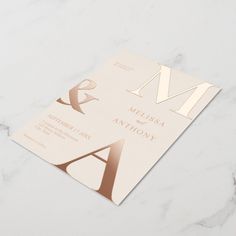 an elegant letter and monogrammed wedding card on a marble surface with gold foil