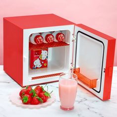 a hello kitty mini fridge with strawberries next to it and a glass of milk