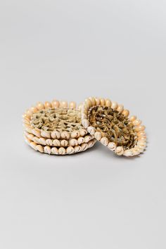 two baskets made out of wood beads on a white background, one has a woven lid and the other is decorated with pearls