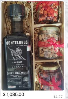 a bottle of liquor sitting in a wooden box next to other jars filled with nuts