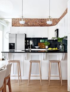 a kitchen with white cabinets and wooden stools in front of an island countertop