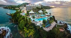 an aerial view of the resort and pool at sunset or sunrise, overlooking the ocean