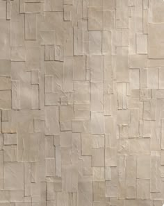 an abstract wall made up of squares and rectangles in neutral tones, with a bench on the side