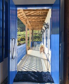 an open door leading to a covered porch with blue shutters and benches on either side