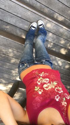 a woman laying on top of a wooden bench