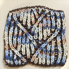 a crocheted dishcloth is shown on a white surface with blue, brown and pink colors