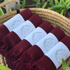 four folded cards are placed in a wicker basket with greenery around them and on top of each other