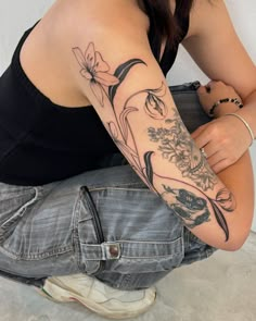 a woman sitting on the ground with her arm tattooed