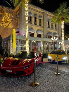 a red sports car parked in front of a tall building at night with palm trees