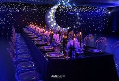 a long table is set up with clear chairs and blue lights on the walls behind it