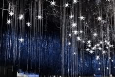 some white stars hanging from the ceiling in front of a blue wall with lights on it