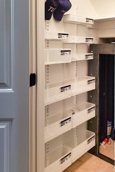 an empty closet with white bins on the wall and several hats hanging from the ceiling