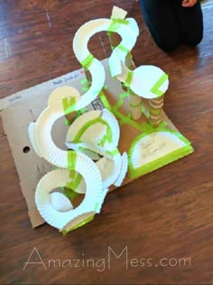 some paper plates are sitting on the floor with green tape around them and two people standing next to it