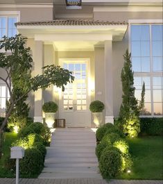 a white house with steps leading to the front door and trees on either side of it