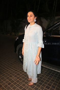 a woman standing in front of a car at night with her hand on her hip