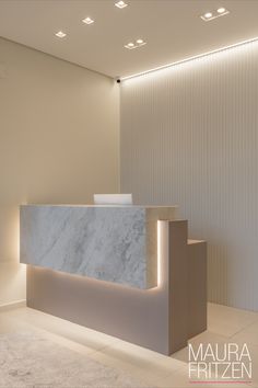 a white marble reception counter in a modern office setting with lights on the wall and carpeted flooring