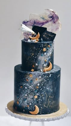 a three tiered black cake with stars and moon decorations