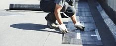 a man working on the side of a building with a roof shingled down to it