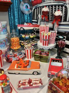 a table topped with lots of candy and candies next to a truck filled with popcorn